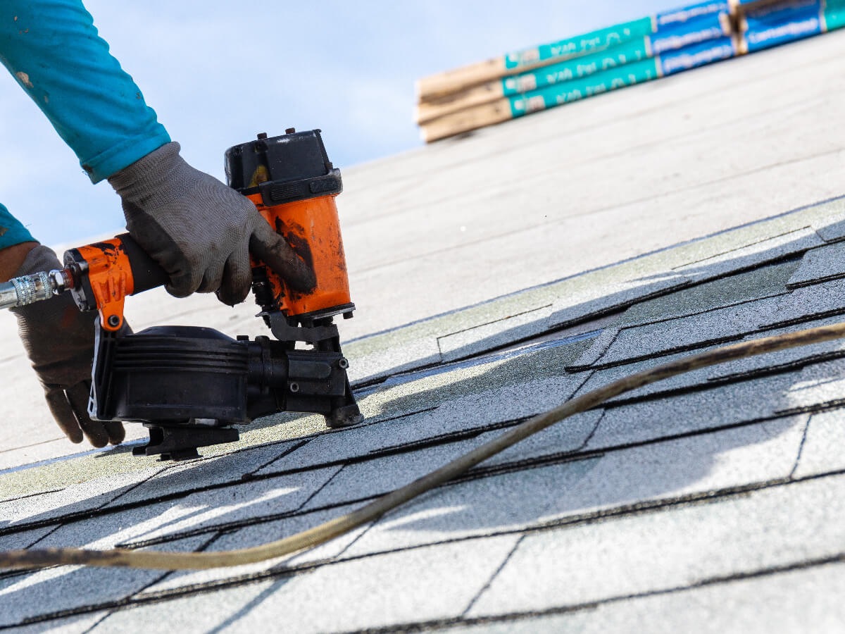 Roofer Using Pneumatic Nail Gun to Install Shingles in Frisco Texas