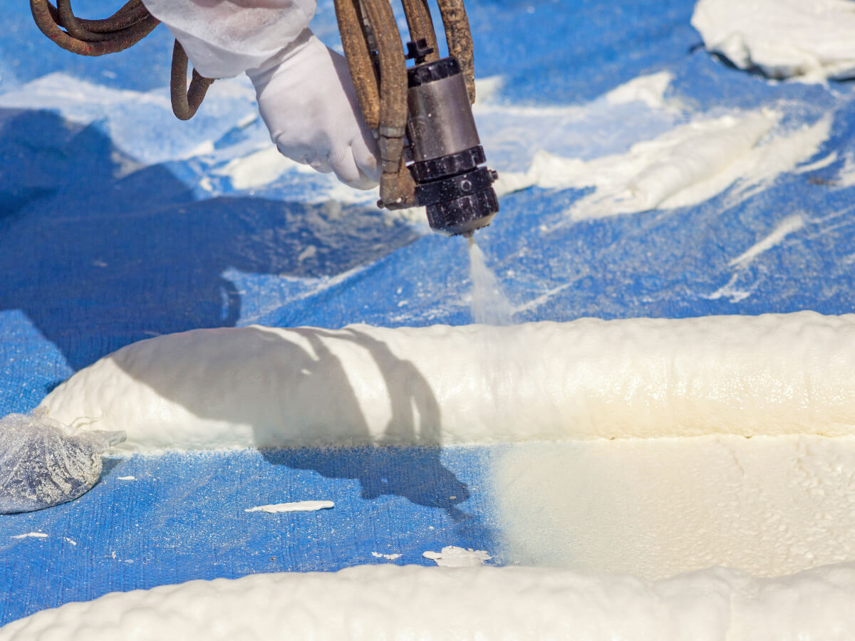 Roofer in Protective Clothing Installing Polyurethane Roof Coating