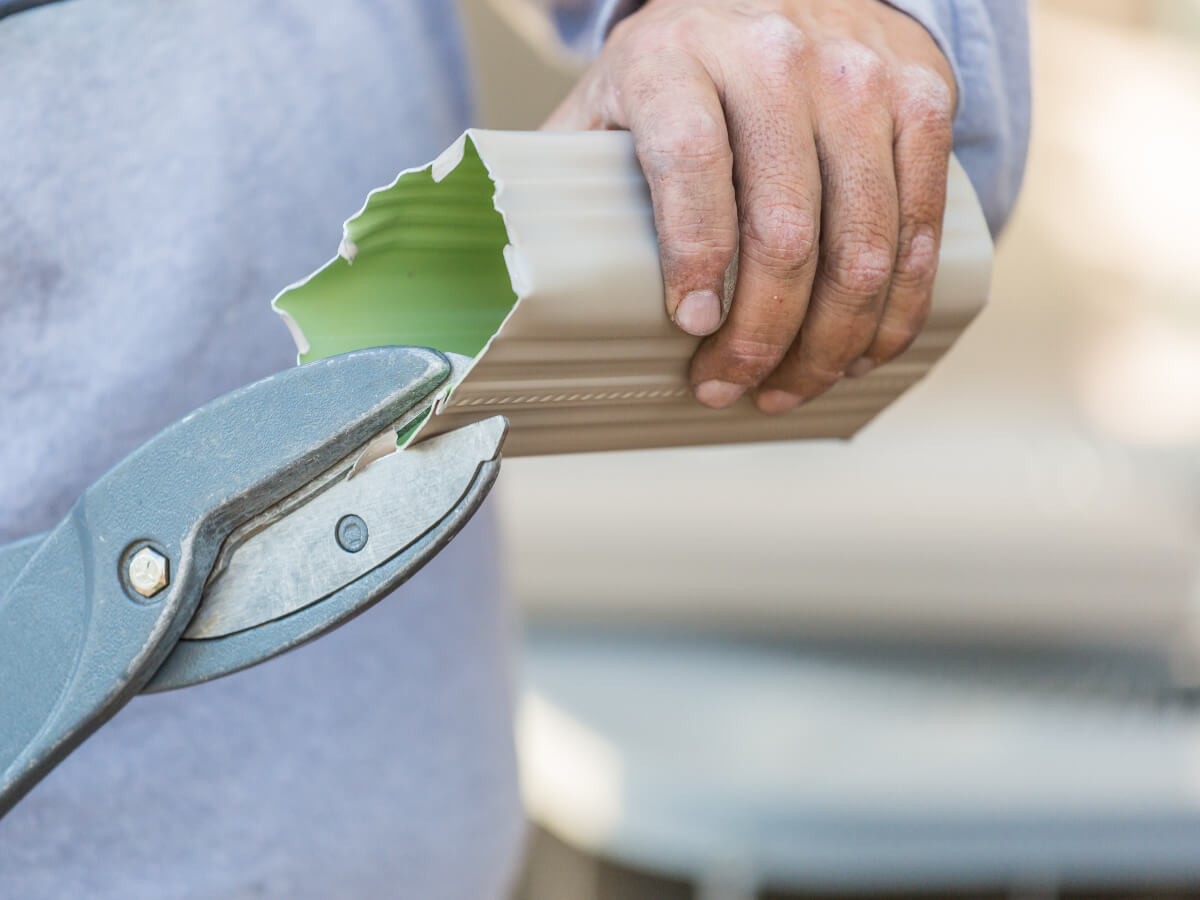Roofer Repairing Gutter Downspout on Home in Frisco Texas